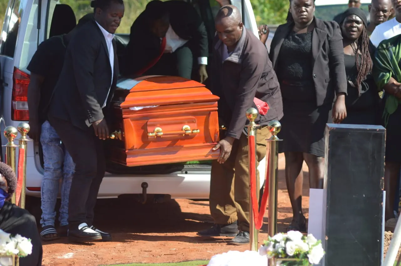 A coffin being carefully carried from a funeral vehicle