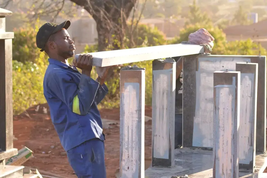 Craftspeople carefully positioning a granite slab on memorial pillars