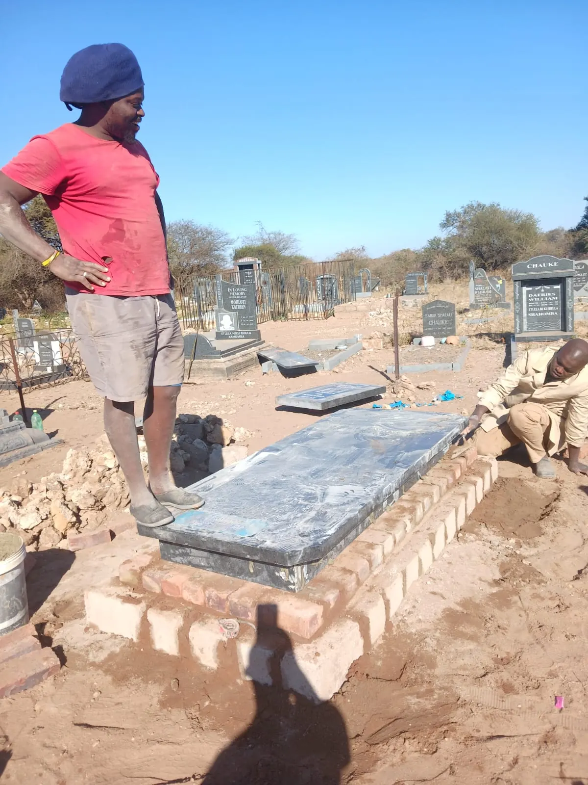 Team preparing granite over a brick memorial base